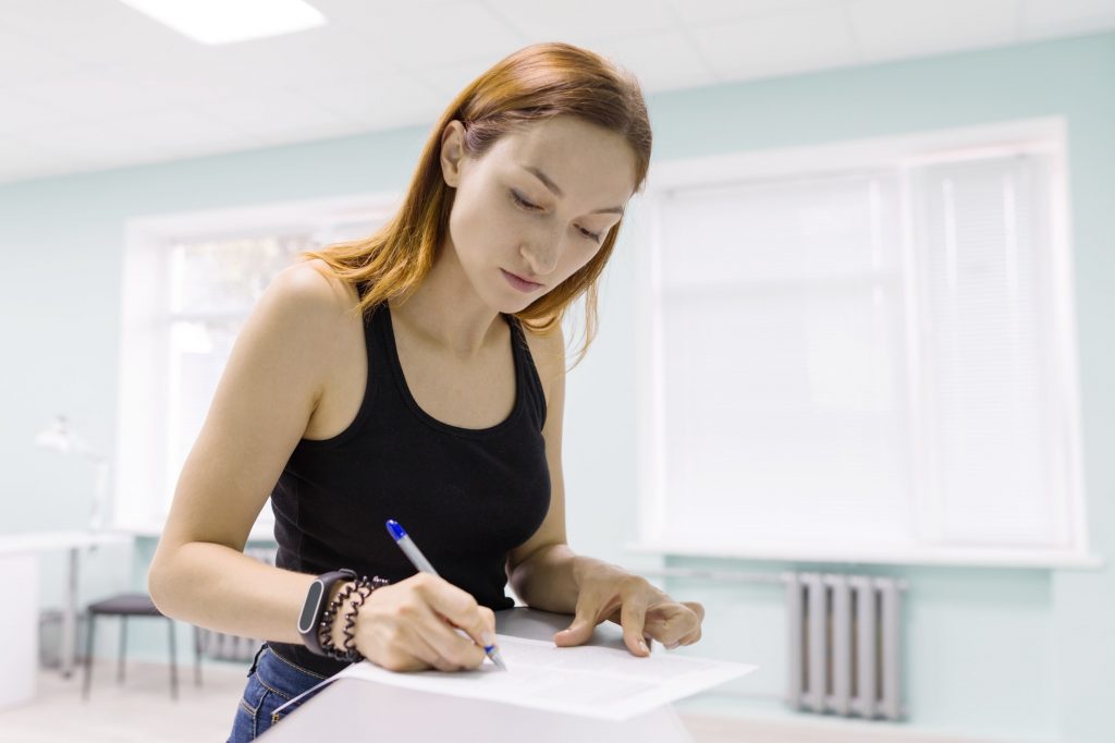 Young beautiful woman signing business papers indoors